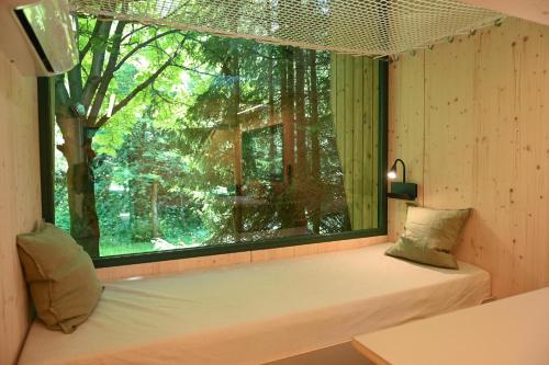 a window seat in a room with a large window at Green Tiny Village Harz - Tiny House Nook 20 in Osterode