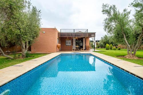 a swimming pool in front of a house at Villa privée a Agafay a Marrakech 