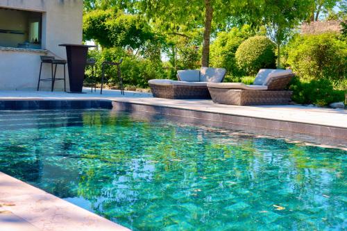 - une piscine avec 2 chaises longues dans l'établissement La Goronière - Superbe Charentaise rénovée - 2 logements - Piscine chauffée, à Saint-Laurent-de-la-Barrière