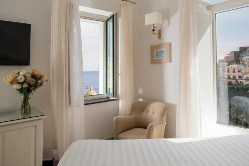 a bedroom with a bed and a chair and a window at Hotel Savoia in Positano