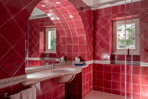 a red bathroom with a sink and a mirror at Hotel Savoia in Positano