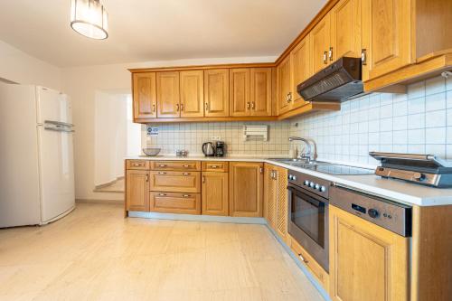 a kitchen with wooden cabinets and a white refrigerator at Arte Lindos Suites in Líndos