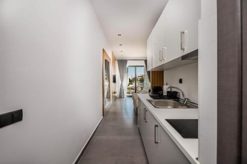 a kitchen with white cabinets and a sink at SOL Luxus Studio in Kallithea Halkidikis