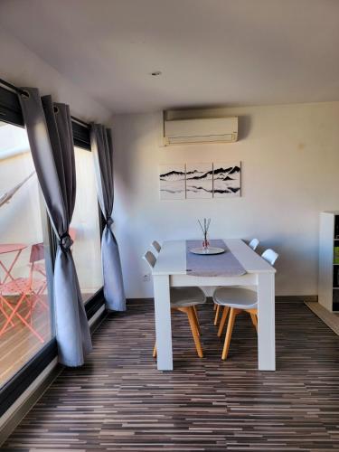 une salle à manger avec une table et des chaises blanches dans l'établissement Béziers, à Béziers