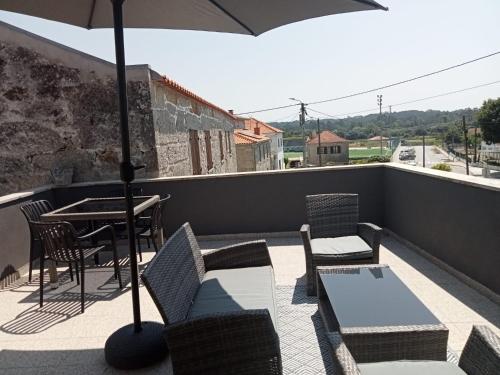 a balcony with a table and chairs and an umbrella at Casa do beco Martinho in Viana do Castelo