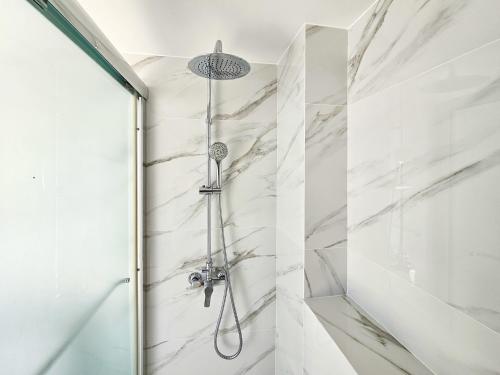 a shower in a bathroom with white marble walls at Nissi beach villa Azure in Ayia Napa