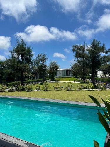 a blue swimming pool with a house in the background at DSD Resort in Háº£i Háº­u
