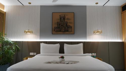 a bedroom with a large bed with white sheets at Seasons Rajkot in Rajkot