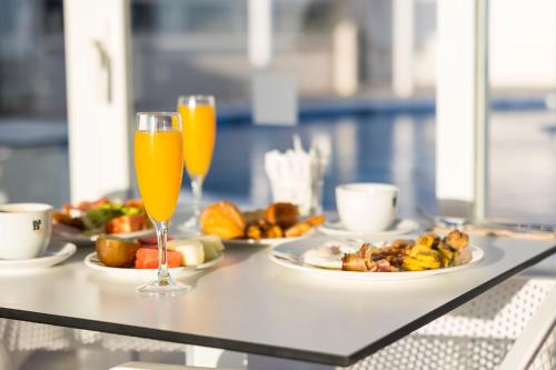 two glasses of orange juice and plates of food on a table at Hotel Boutique TAO Caleta Mar in Corralejo