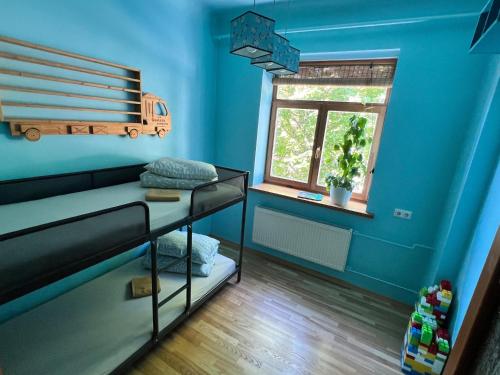 een blauwe kamer met een stapelbed en een raam bij Blakus bērnu pilsētiņai un pludmalei in Ventspils