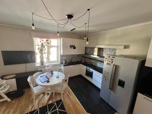 een keuken met een tafel en een witte koelkast bij Blakus bērnu pilsētiņai un pludmalei in Ventspils