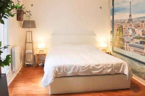 une chambre avec un lit blanc et une grande fenêtre dans l'établissement Cosy and practical studio in the heart of 15ᵉ, à Paris