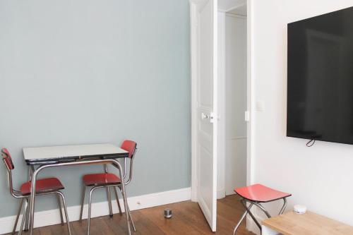 une pièce avec une table, des chaises et une télévision dans l'établissement Design apartment with WiFi in the heart of Paris, à Paris