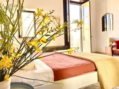 a bedroom with a bed with a vase with yellow flowers at Palazzo 700 in Castellammare del Golfo