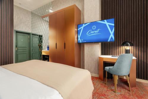 a bedroom with a bed and a tv on a wall at Carat Hotel Yerevan in Yerevan