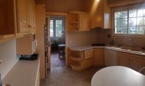 une cuisine avec des armoires en bois et un comptoir blanc dans l'établissement Au petit Ruisseau, maison à Capbreton, à Capbreton