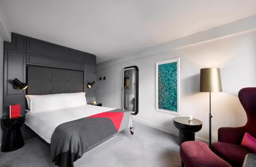 a bedroom with a bed and a red chair at Sea Containers London in London