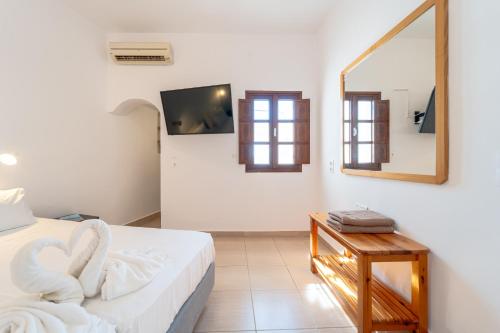 a bedroom with a bed and a mirror and a table at Arte Lindos Suites in Líndos