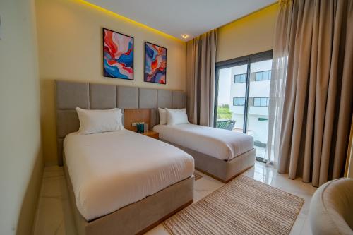 a hotel room with two beds and a window at Rafiny Hôtel in Ksar el Kebir