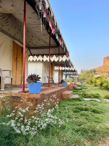 a building with a porch with flowers in the grass at Murali Guesthouse Hampi in Hampi