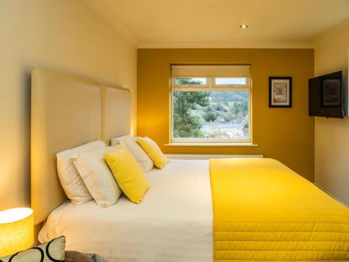 a bedroom with a bed with yellow and white pillows at Bagshaw Lodge in Bakewell