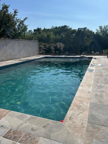 une piscine avec de l'eau bleue dans une cour dans l'établissement Nouveau gîte en Provence avec piscine sur Arles, à Arles