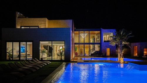 a swimming pool in front of a house at night at Enchanted Harmony by AURA in Żurrieq