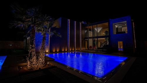 a swimming pool with blue lighting in front of a house at Enchanted Harmony by AURA in Żurrieq