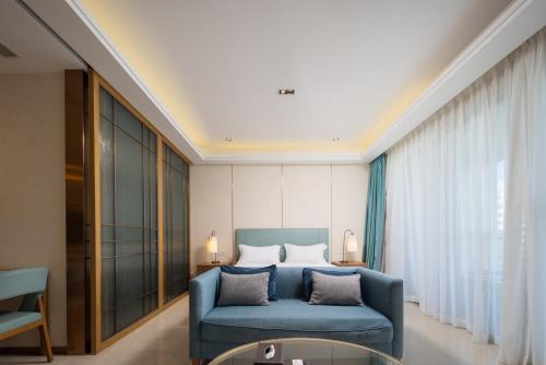 a bedroom with a blue couch and a bed at Sanya Haitang Bay Ocean State International Resort Hotel in Sanya