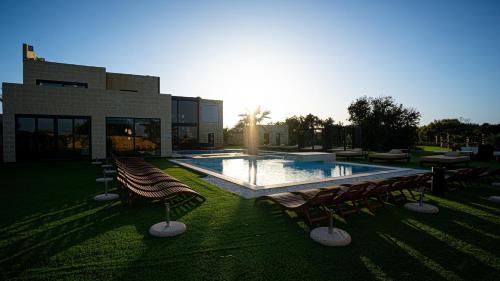 a swimming pool with several chairs and a building at Enchanted Harmony by AURA in Żurrieq