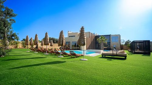a row of chairs and a pool in a grass field at Enchanted Harmony by AURA in Żurrieq