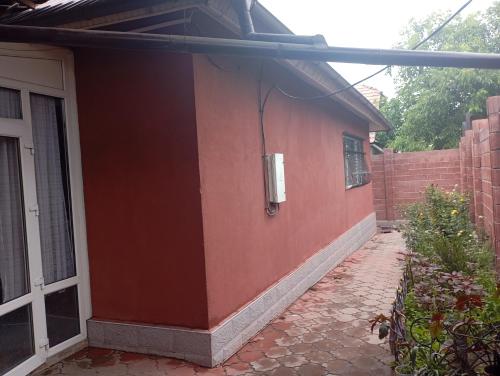 a red house with a door and a brick wall at happy home in Bishkek