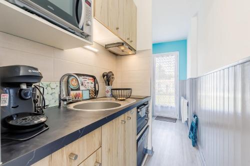 une petite cuisine avec un évier et un micro-ondes dans l'établissement 11 - Le Rossignol - Village vacances, à Maché