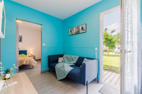 Cette chambre bleue comprend un canapé et un lit. dans l'établissement 11 - Le Rossignol - Village vacances, à Maché