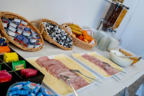 a table with cheese and meats and baskets of fruit at Hotel Du Gave in Lourdes