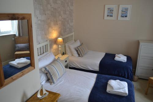 two beds in a hotel room with a mirror at The Ridge in Menai Bridge