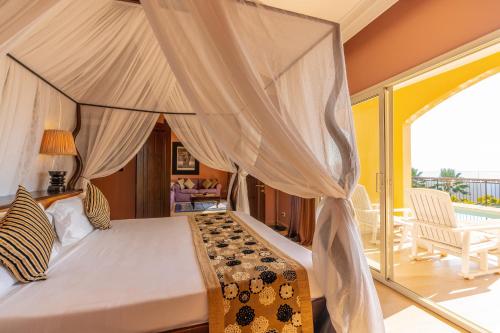 a bedroom with a canopy bed and a balcony at Riu Palace Zanzibar - All Inclusive in Nungwi