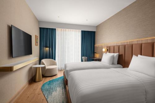 a hotel room with two beds and a flat screen tv at Courtyard by Marriott Prishtina in Pristina
