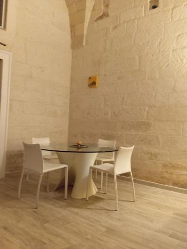 a dining room with a table and white chairs at Lapis Domus in Lecce