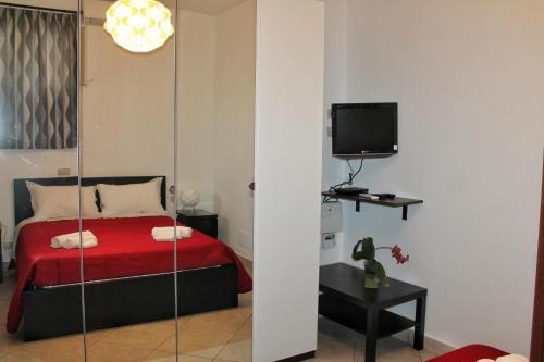 1 dormitorio con cama roja y TV en La Casetta, en Cefalú