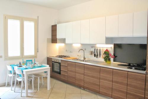 cocina con mesa y cocina con armarios blancos en La Casetta, en Cefalú