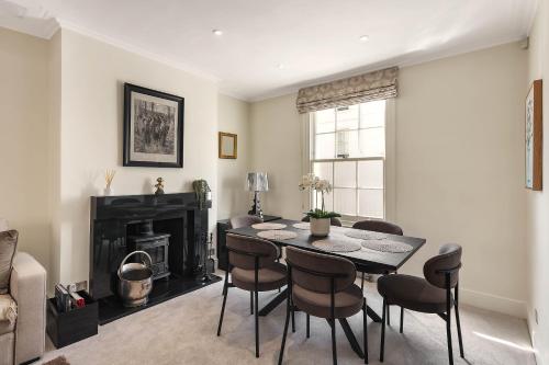 a dining room with a table and chairs and a fireplace at Knightsbridge Townhouse Private Terrace & Harrods in London