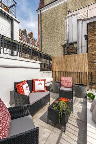a patio with chairs and tables on a balcony at Knightsbridge Townhouse Private Terrace & Harrods in London
