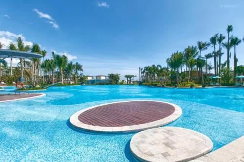 a large swimming pool with blue water and palm trees at Sanya Haitang Bay Ocean State International Resort Hotel in Sanya