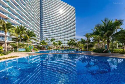 a swimming pool in front of a tall building at Sanya Haitang Bay Ocean State International Resort Hotel in Sanya