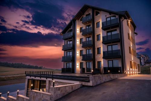 a building with a sunset in the background at Villa Di Montagna wellness & spa in Zlatibor