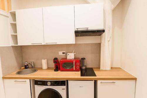 - une cuisine avec un four micro-ondes rouge et un évier dans l'établissement 2 pieces avec mezzanine et deco design - Paris 9, à Paris