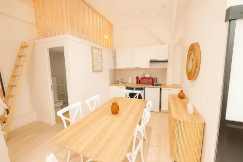 une cuisine et une salle à manger avec une table et des chaises en bois dans l'établissement 2 pieces avec mezzanine et deco design - Paris 9, à Paris
