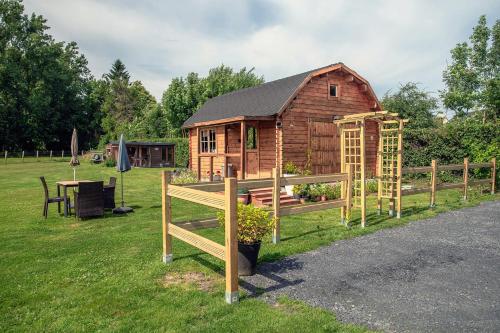 a wooden cabin in the grass with a fence at Wooden Lodge in Saint-Blimont