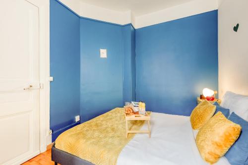 - une chambre avec des murs bleus et un lit avec une table de chevet dans l'établissement Le Cocoon Doré, à Clichy